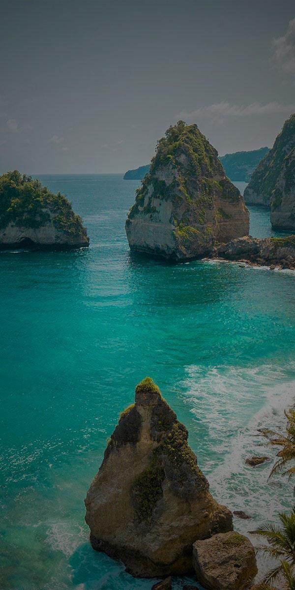 Person relaxing on rocky shoreline by turquoise sea under clear sky – luxury coastal travel destination inspiring adventure, holiday planning, and tourism on Travelcation